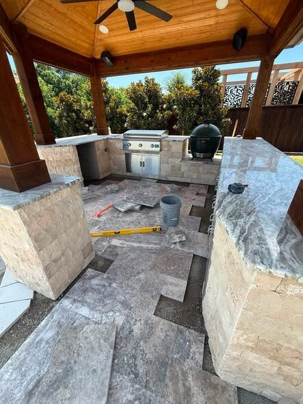 Covered outdoor kitchen with a built-in grill and Big Green Egg on travertine